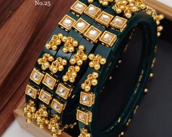 Puede incluir: Conjunto de cuatro pulseras de brazalete verdes con detalles dorados y piedras de cristal transparentes. Las pulseras están decoradas con pequeñas bolas doradas y tienen una etiqueta que dice 'D.No.06 Brass High Gold Kundan Ghughari Bangels Size. 2/4. 2/6. 2/8. 2/10 No.25'.
