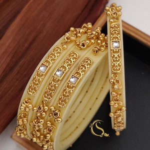 May include: Set of four ivory bangles with gold accents and clear stones. The bangles have a decorative design and are stacked on top of each other. The text "No:-35. 4-pice Bengal's 22/2.4/2.6/2.8/" is printed below the bangles.