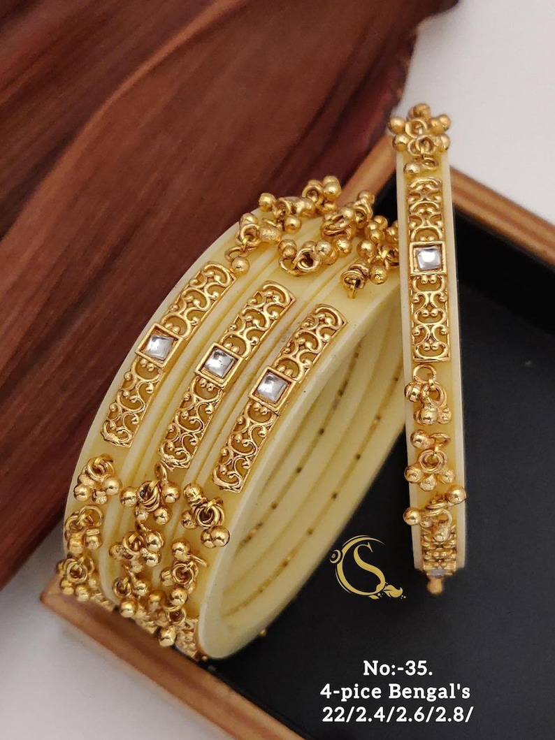 May include: Set of four ivory bangles with gold accents and clear stones. The bangles have a decorative design and are stacked on top of each other. The text "No:-35. 4-pice Bengal's 22/2.4/2.6/2.8/" is printed below the bangles.