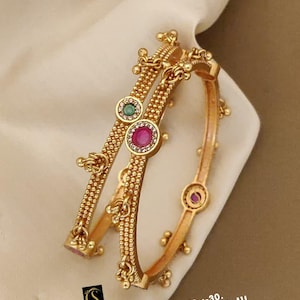 May include: Two gold-toned bangles featuring a textured beaded surface, small dangling gold spheres, and circular settings containing green and pink stones. The text on the image reads: No:-30. Daily Wear Kadli 2.4/2.6/2.8/2.10/ D:-1915.