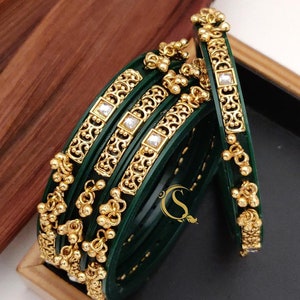 May include: Set of four green and gold bangles with intricate designs and clear rhinestones. The bangles are stacked and arranged in a box. No:-35. 4-pice Bengal's 22/2.4/2.6/2.8/