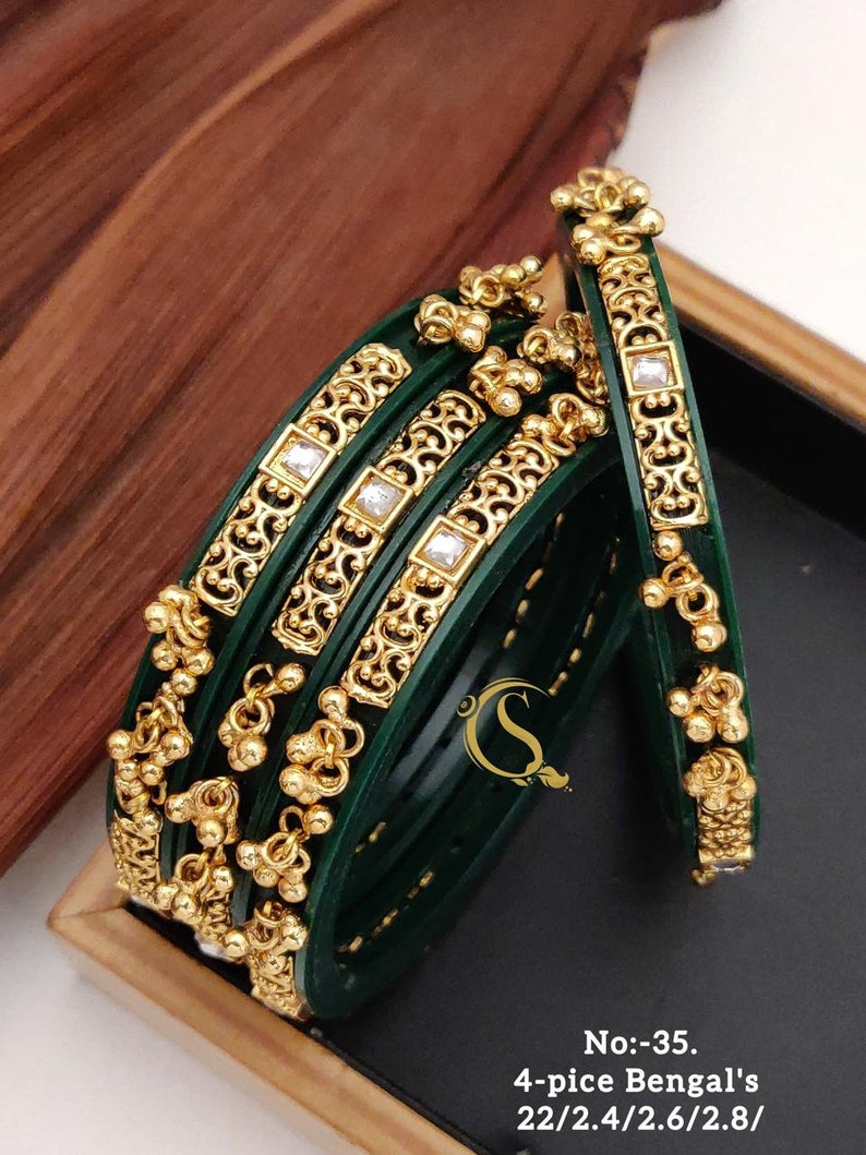 May include: Set of four green and gold bangles with intricate designs and clear rhinestones. The bangles are stacked and arranged in a box. No:-35. 4-pice Bengal's 22/2.4/2.6/2.8/