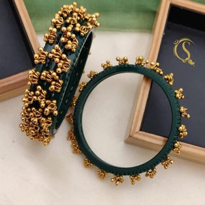 May include: Four green bangles with gold accents. The bangles are decorated with small gold balls and have a floral design. The text "No:-29. 4-Pis Chudi 2.2/2.4/2.6/2.8/2.10/" is printed below the bangles.