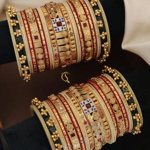 Può includere: Un set di 14 braccialetti dorati con accenti rossi, verdi e bianchi. I braccialetti sono decorati con disegni intricati e pietre preziose. No:-119. ANTIQUE CHUDLS 2.4/2.6/2.8/ D:-04+1556