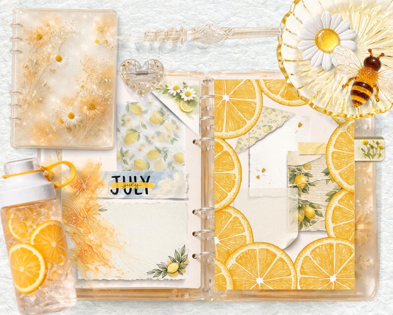 May include: A clear plastic water bottle filled with lemon slices, a ring-bound planner featuring lemon and daisy illustrations, a heart-shaped resin charm, and a decorative glass dish with a daisy and bee figurine on a textured white background.