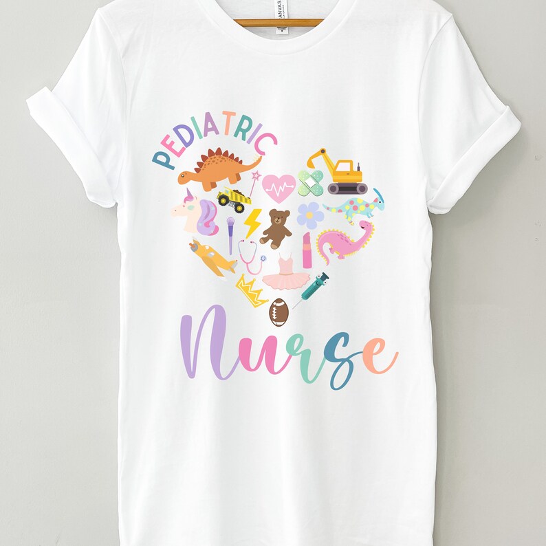 May include: White t-shirt with a pink, blue and yellow heart design featuring various children's toys and the text "PEDIATRIC NURSE".