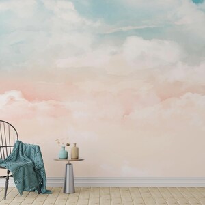 Puede incluir: Un mural de estilo acuarela con un cielo de suaves tonos rosas y azules, que se asemeja a las nubes. Una silla negra con una manta turquesa está a la izquierda. Una pequeña mesa sostiene jarrones. El suelo es de tablones de madera.