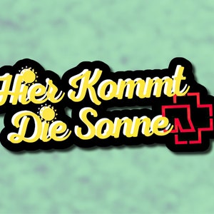 May include: Black and yellow sticker with the text "Hier Kommt Die Sonne" and a red and white cross.