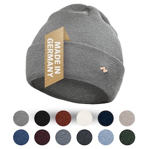 Könnte beinhalten: Graue Mütze mit einem braunen Etikett, auf dem "Made in Germany" steht. Die Mütze ist aus weichem, gestricktem Stoff gefertigt. Die Mütze ist in verschiedenen Farben erhältlich.