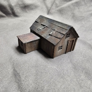 May include: A small wooden model of a weathered barn with a corrugated metal roof and a small shed attached to the side.