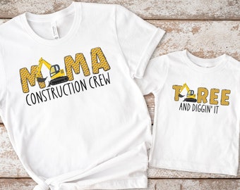 Peut inclure: Deux t-shirts blancs sur le thème de la construction. Le plus grand t-shirt dit "Mama Construction Crew" avec un graphique d'excavatrice jaune. Le plus petit t-shirt dit "Too  Tree and Diggin' It" avec un graphique d'excavatrice jaune.