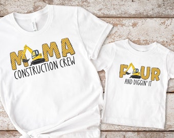 Peut inclure: Deux t-shirts blancs sur le thème de la construction. Le plus grand t-shirt dit "Mama Construction Crew" avec un graphique d'excavatrice jaune. Le plus petit t-shirt dit "Four and Diggin' It" avec un graphique d'excavatrice jaune.