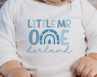 May include: White long-sleeved onesie with blue text that reads "Little Mr One" with a blue and white rainbow design and the words "derland" underneath.