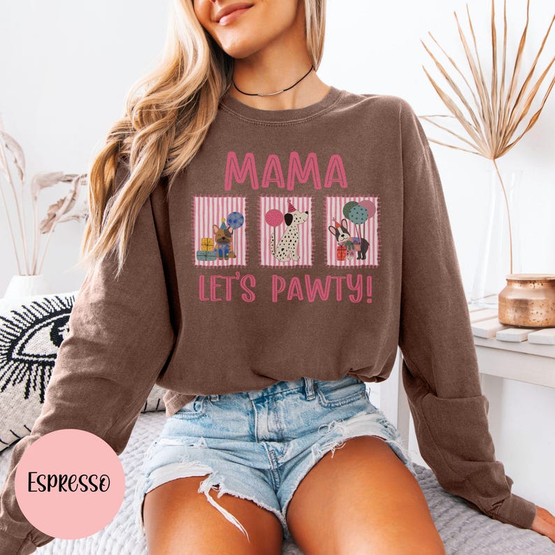 May include: Espresso-colored sweatshirt with the text "MAMA LET'S PAWTY!" and three cartoon dog illustrations. The design includes pink and white striped boxes with dogs holding balloons and gifts. The sweatshirt is a crew neck style.