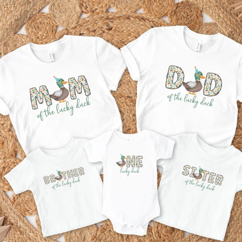 Pode incluir: Um conjunto de cinco camisetas brancas com um desenho de pato e texto que diz "M&atilde;e do pato da sorte", "Pai do pato da sorte", "Irm&atilde;o do pato da sorte", "Um pato da sorte" e "Irm&atilde; do pato da sorte".