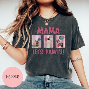 May include: Dark gray t-shirt with the text "MAMA LET'S PAWTY!" in pink. The shirt features three pink striped boxes with illustrations of dogs holding balloons and gifts. The word "Pepper" is in a pink circle.
