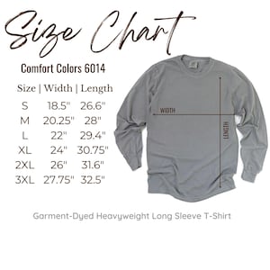 May include: A gray long-sleeve t-shirt with a size chart. The chart lists sizes S to 3XL, with width and length measurements in inches. The shirt is labeled as a Garment-Dyed Heavyweight Long Sleeve T-Shirt.