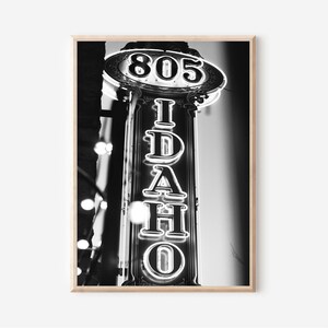 May include: Black and white photograph of a neon sign that reads "IDAHO" with the number "805" above it.