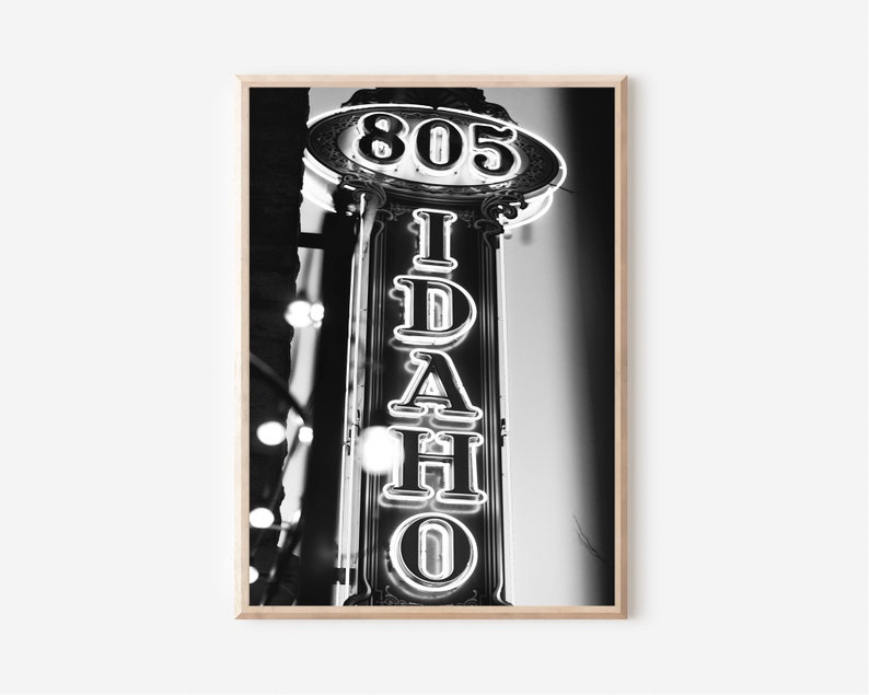 May include: Black and white photograph of a neon sign that reads "IDAHO" with the number "805" above it.