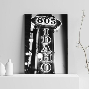 May include: Black and white photograph of a neon sign that reads "805 IDAHO" in a vintage style.
