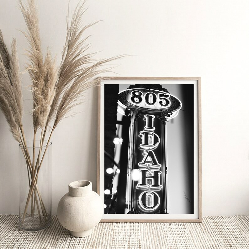 May include: Black and white photograph of a neon sign that reads "IDAHO" with the number "805" above it.