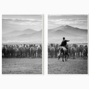 May include: Black and white print of a herd of horses running across a field, with a rider on horseback in pursuit. The background features mountains and a cloudy sky, creating a dramatic landscape scene.