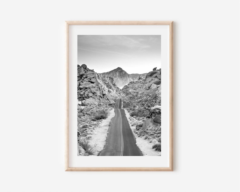 May include: A black and white photograph of a winding road through a desert mountain range.