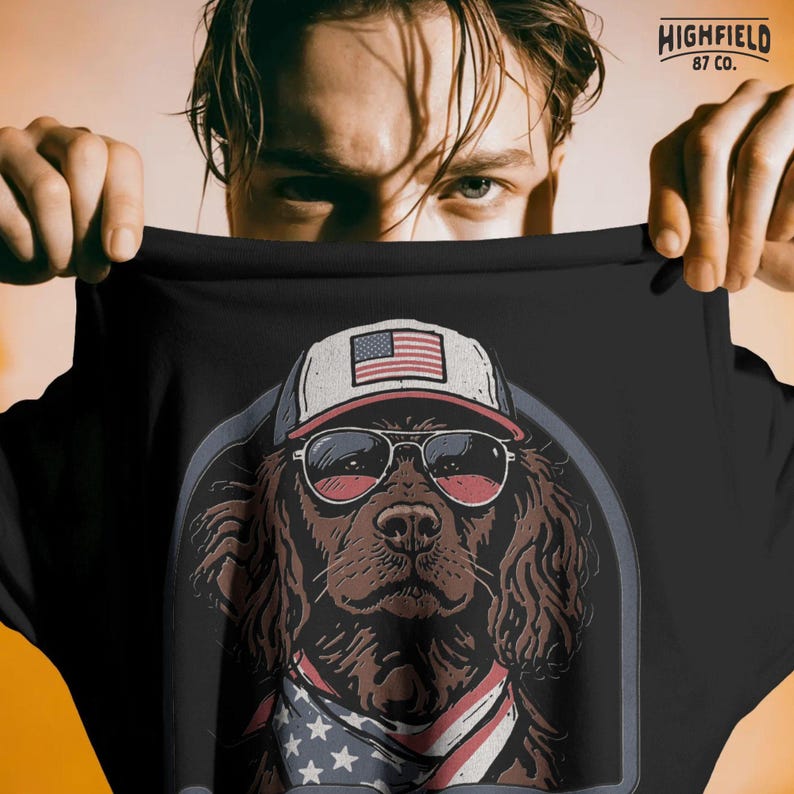 American flag dog PNG featuring a spaniel with sunglasses and patriotic bandana inside a rounded badge frame.
