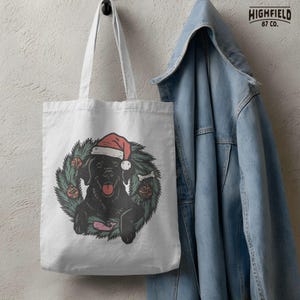 Pet Christmas design showing black Labrador retriever in pine wreath with red ornaments. Digital file for holiday sublimation.