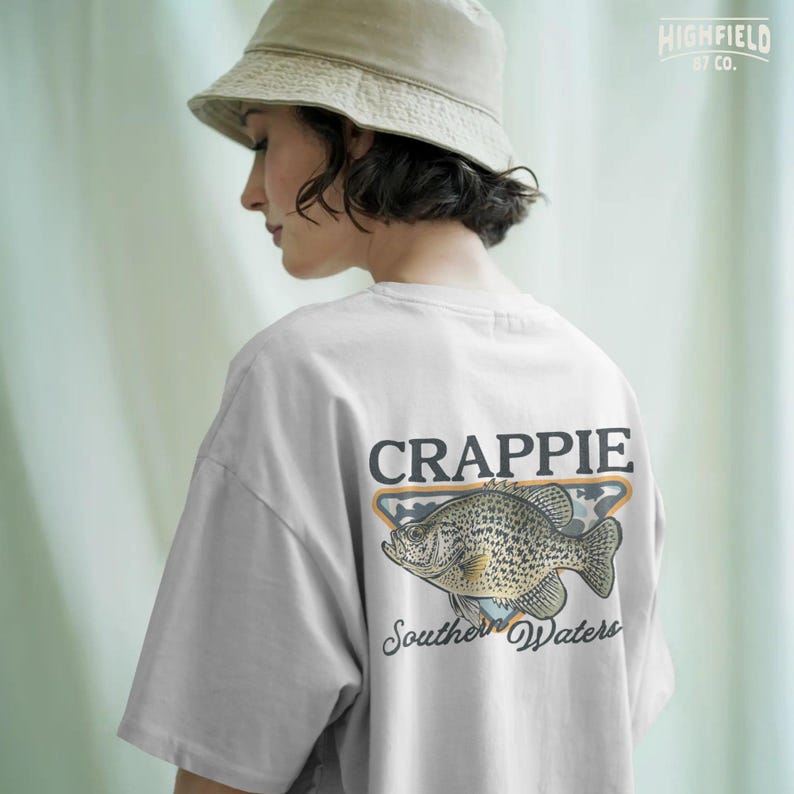 Crappie shirt PNG showing a freshwater panfish in front of a camo badge with large black Crappie text and script Southern Waters lettering.
