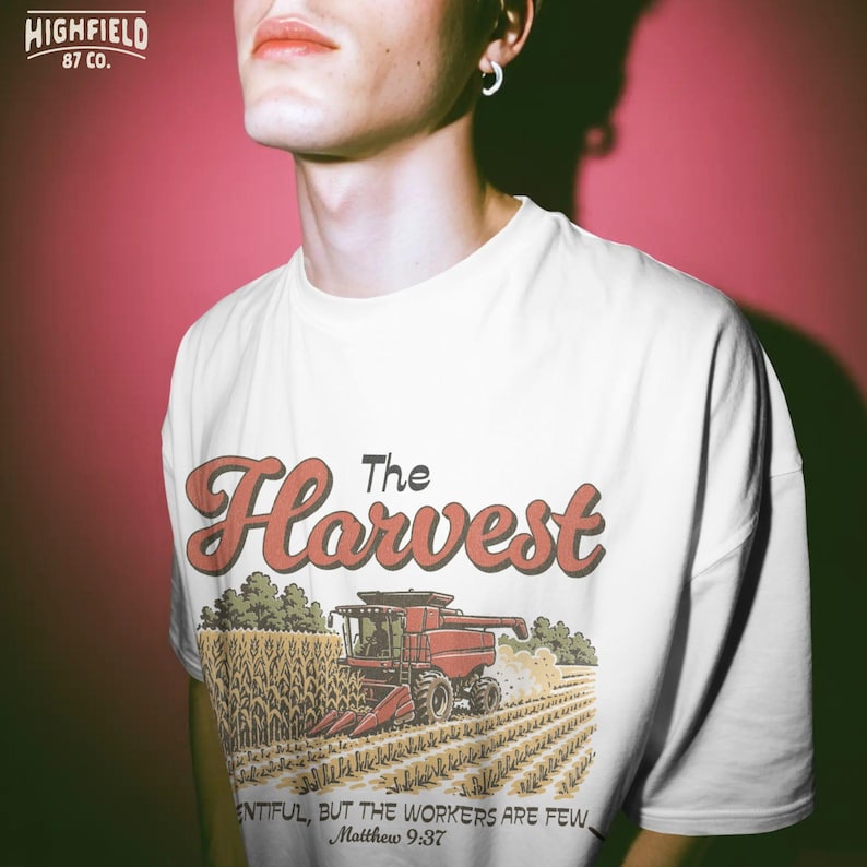 Farmer shirt PNG showing a combine in a corn field with The Harvest lettering for Christian agriculture apparel.