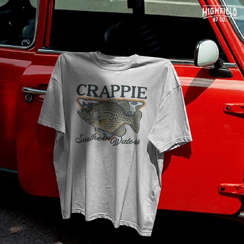 Fishing shirt PNG featuring a speckled crappie fish with camo background, orange frame, and Southern Waters wording for freshwater anglers.