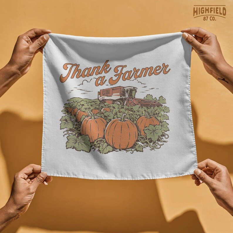 Farmer appreciation shirt design featuring pumpkins in a harvest field with a combine harvester and bold “Thank a Farmer” script in a warm seasonal farm composition.