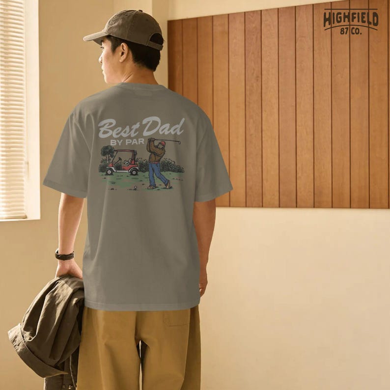 Golf shirt PNG with Best Dad By Par text, Bigfoot golfer, golf cart, and course scenery, ideal for dad gifts and funny golf apparel designs.