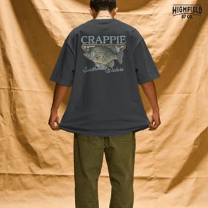 Crappie fisherman PNG showing a detailed panfish illustration with bold fish name lettering and southern fishing theme for outdoor apparel designs.