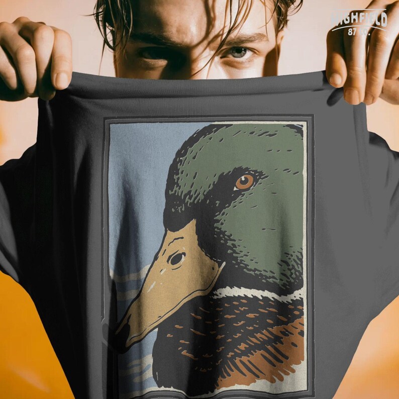 Mallard duck profile portrait drawn in a bold outdoor art style, featuring flat muted colors and detailed feather texture around the neck and chest. The duck head is centered within a clean rectangular frame, designed as a high quality PNG file for duck hunting merchandise, waterfowl apparel, and printable wildlife graphics.