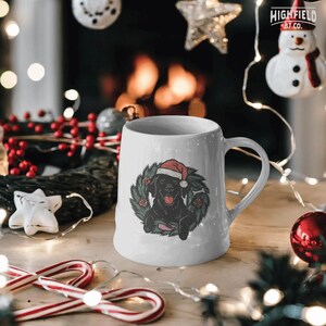 Labrador Christmas PNG download featuring festive black lab wearing Santa hat inside decorated wreath. Great for pet holiday projects.