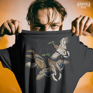 Duck season PNG with flying mallards and bare branches, designed for hunters and waterfowl lovers.