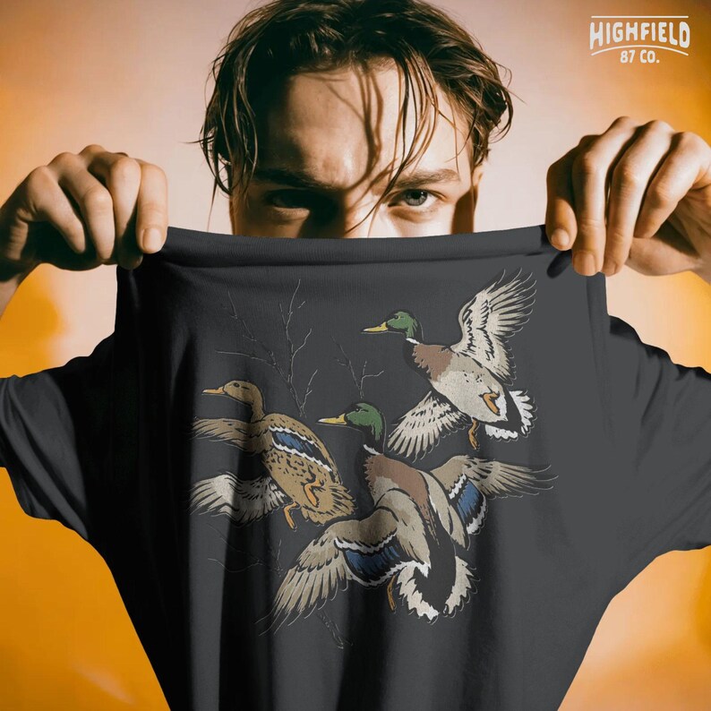 Duck season PNG with flying mallards and bare branches, designed for hunters and waterfowl lovers.