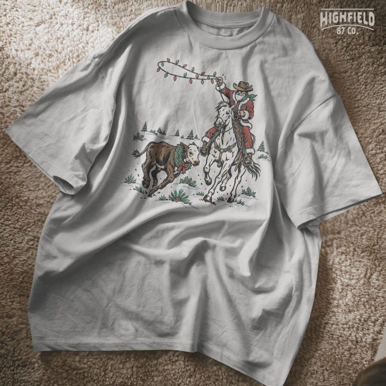 Vintage-style Western Christmas design showing Santa on horseback beside a running calf with pine trees and snowy ground in the background.