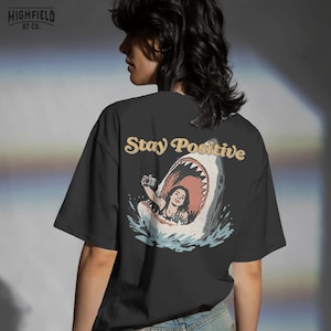 funny shark scene with woman taking selfie inside shark mouth and stay positive phrase, beach humor illustration for summer png shirts and ocean themed apparel
