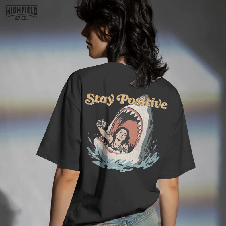 funny shark scene with woman taking selfie inside shark mouth and stay positive phrase, beach humor illustration for summer png shirts and ocean themed apparel
