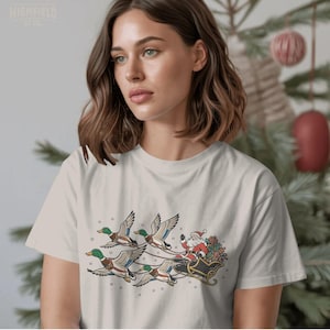 Holiday waterfowl design featuring Santa waving from his sleigh while four green-headed mallard ducks fly together across a snowy scene.