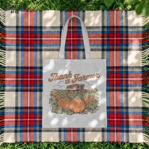 Thank a Farmer shirt PNG showing a pumpkin harvest field with large foreground pumpkins, green vines, and a combine harvester in the background in a fall farm illustration.