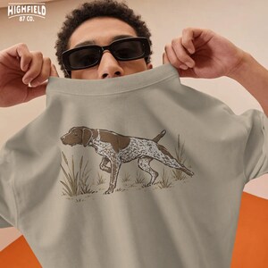 Hunter gift PNG showing a pointing German Shorthaired Pointer in field grass, perfect for bird hunters and sporting dog fans.