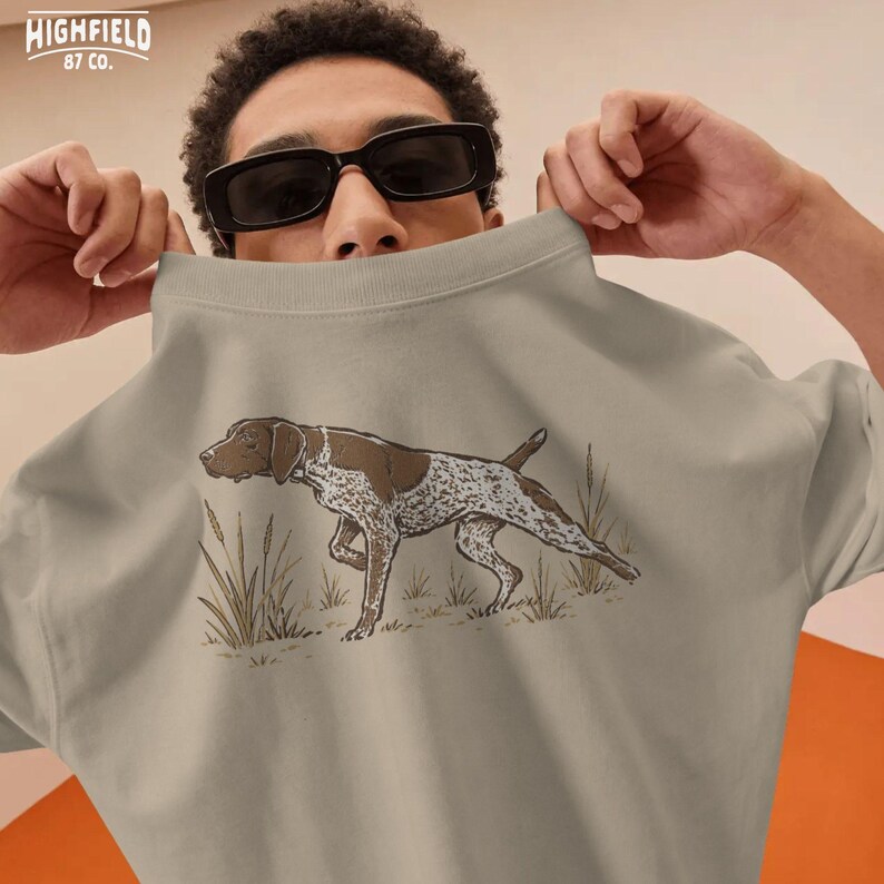 Hunter gift PNG showing a pointing German Shorthaired Pointer in field grass, perfect for bird hunters and sporting dog fans.
