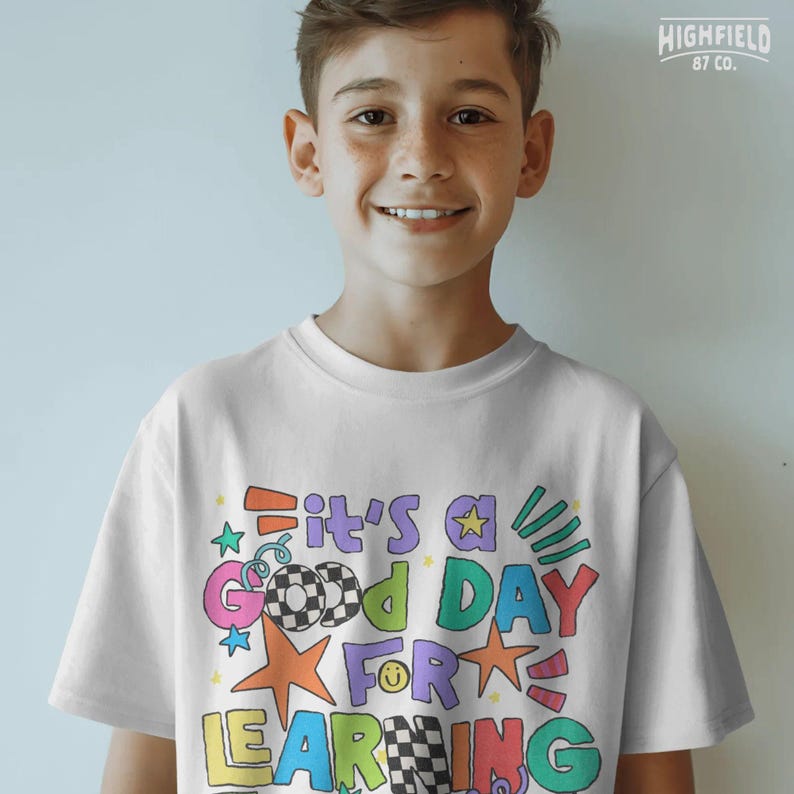 Teacher shirt PNG with a cheerful school quote, colorful star elements, and bold doodle letters for classroom style graphics.