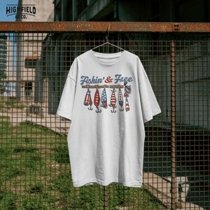 patriotic fishing graphic with multiple fishing lures in red white and blue hanging from rod with bold fishin and free text, detailed hooks and lure shapes for angler design, perfect fishing png for t shirt printing, summer fishing apparel, american themed outdoor graphic, 4th of july fishing design for digital download