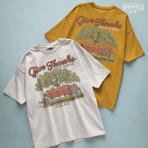 Thanksgiving shirt PNG featuring Give Thanks for He Is Good text with pumpkins, fall flowers, wagon, and Christian farm style.