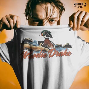 Wood duck PNG illustration with drake duck and bold Woodie Drake lettering, waterfowl themed artwork for shirts